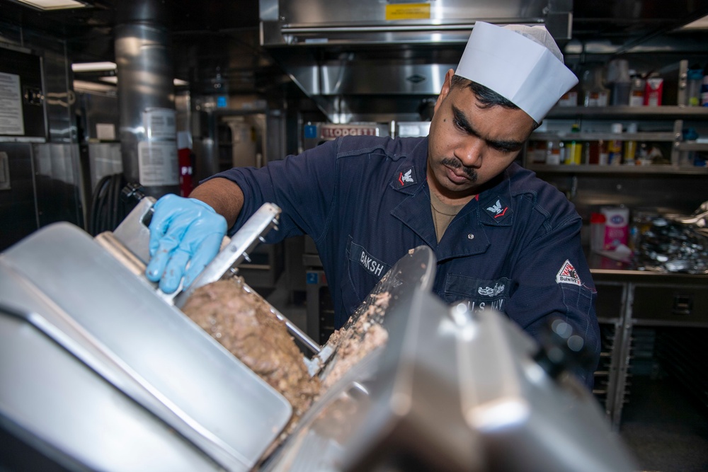 Culinary Specialist 3rd Class Ameir Baksh, from Bronx, N.Y., slices lamb in the galley