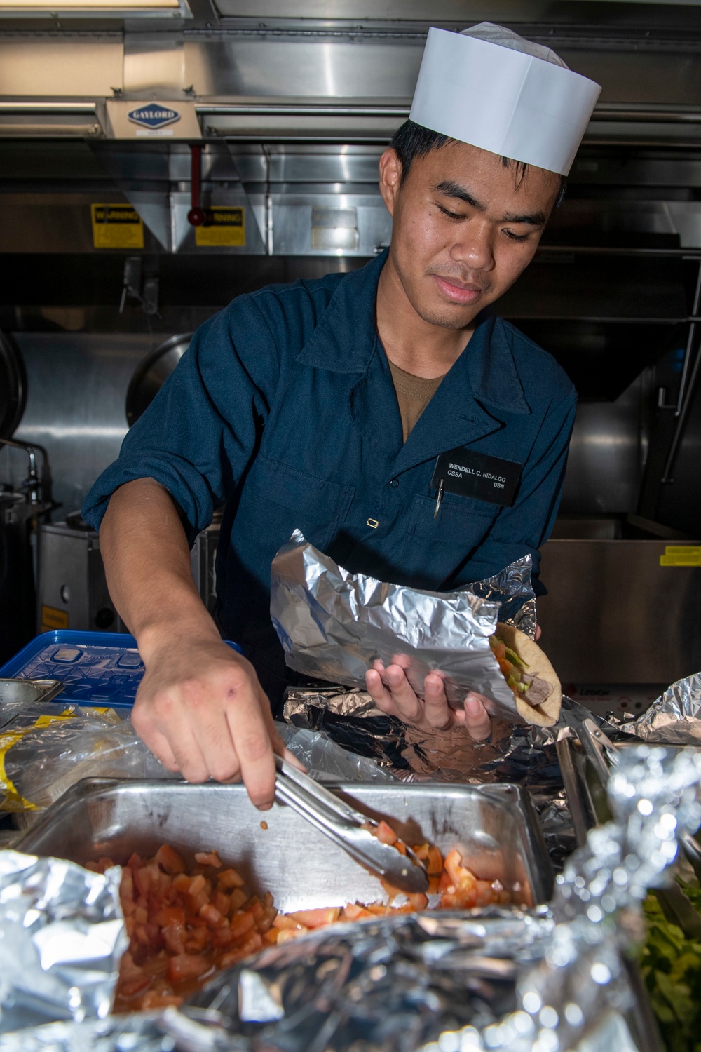 Culinary Specialist Seaman Apprentice Wendell Hidalgo, from Maui, Hawaii, prepares a gyro in the galley