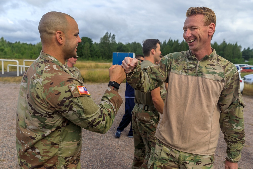 Staff Sgt. Devin Crawford congratulates Rasmus Due after completing of the land obstacle course
