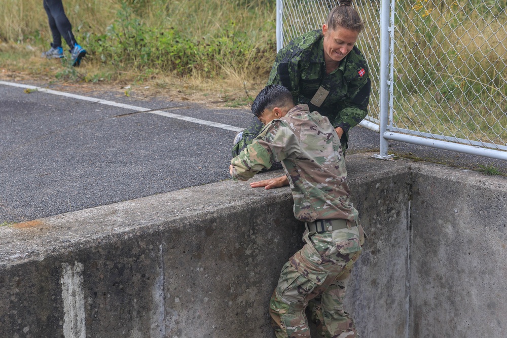 Capt. Mille Hewalo helps her teammate Maj. Nicole Dallocchio up an obstacle
