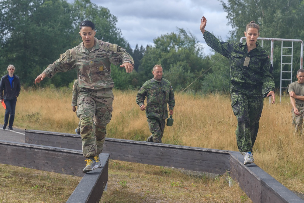 Maj. Nicole Dallocchio and Capt. Mille Hewalo balance on a beam