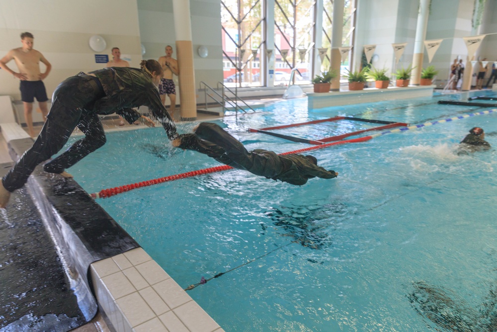 The international women's team dive into the water obstacle course