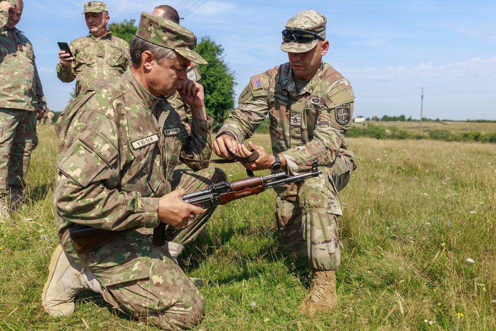 Staff Sgt. Devin Crawford shows a Romania Reserve Soldier rifle marksmanship techniques