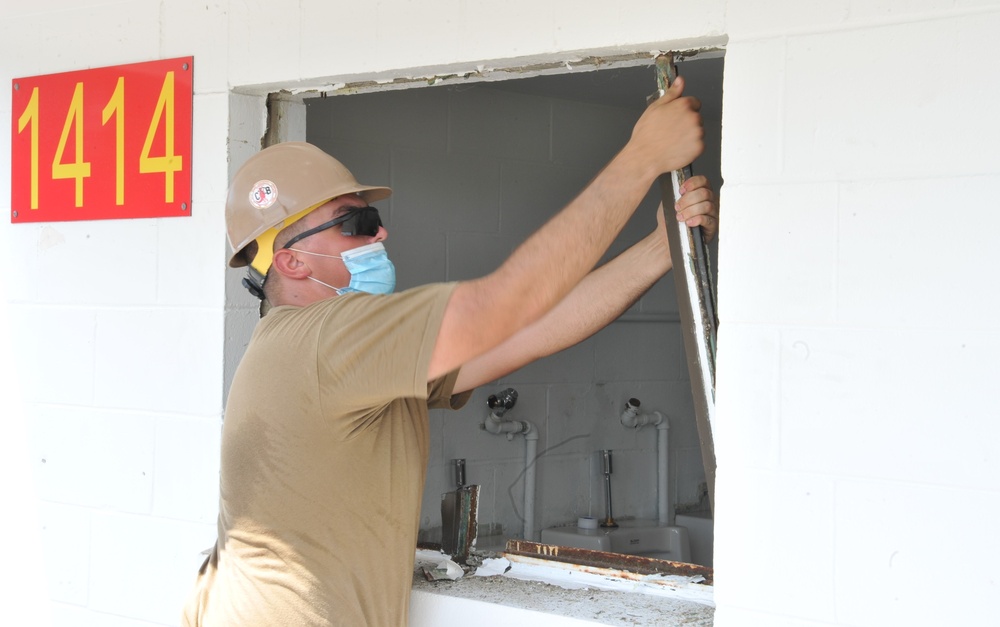 A Seabee assigned to Naval Mobile Construction Battalion (NMCB) 133 repairs a window opening as as part of a bathroom renovation on board Marine Corps Air Station Cherry Point in support of Large-Scale Exercise 2021