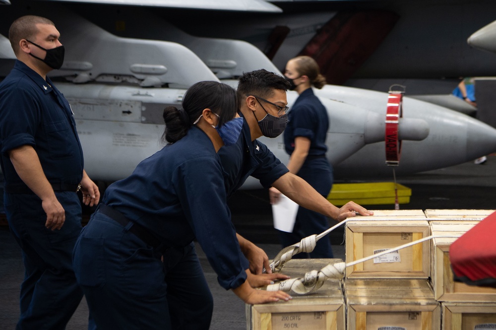 Sailors transport munitions through the hangar bay
