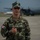 Ramstein Airmen enable Agile Spirit A young male soldier in camouflage uniform stands on an airfield tarmac giving a thumbs-up gesture. He wears a patch on his left sleeve depicting the flag of Georgia (the country), indicating he is a member of the Georgian Armed Forces. A large military transport aircraft, consistent with a C-130 Hercules, is visible in the blurred background.