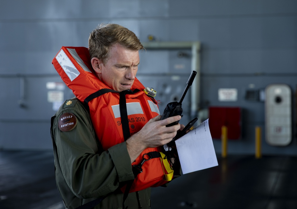 Lt. Cmdr. Doug Stahl, a pilot with Helicopter Sea Combat Squadron (HSC) 23, uses a satellite phone during a man overboard drill aboard expeditionary sea base USS Miguel Keith (ESB 5)