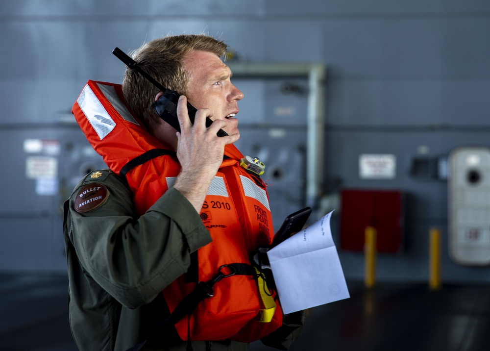 Lt. Cmdr. Doug Stahl uses a satellite phone during a man overboard drill on USS Miguel Keith