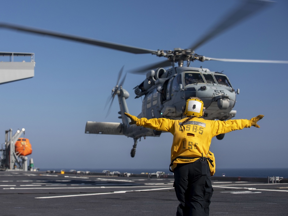 Aviation Boatswain’s Mate 3rd Class Nadezhda Zurbriggen directs an MH-60S Sea Hawk from Helicopter Sea Combat Squadron (HSC) 23 aboard expeditionary sea base USS Miguel Keith (ESB 5)