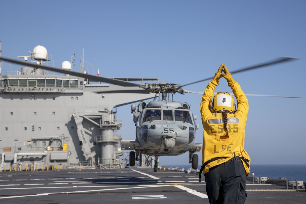 Aviation Boatswain’s Mate 3rd Class Nadezhda Zurbriggen directs an MH-60S Sea Hawk from Helicopter Sea Combat Squadron (HSC) 23 aboard expeditionary sea base USS Miguel Keith (ESB 5)