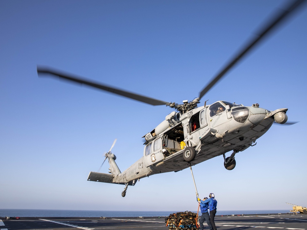 Aviation Boatswain’s Mate Airman Jacobi Easterling, left, and Airman Salva Kritzer attach cargo to an MH-60S Sea Hawk from Helicopter Sea Combat Squadron (HSC) 23 aboard expeditionary sea base USS Miguel Keith (ESB 5)