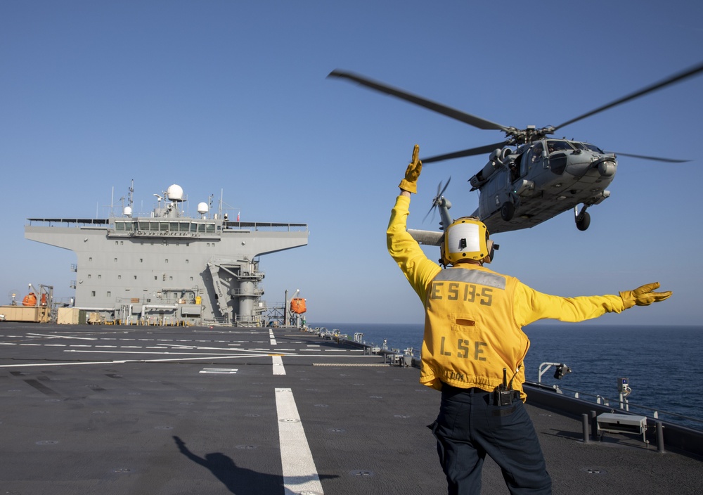 Aviation Boatswain’s Mate Airman Ethan Bowser directs an MH-60S Sea Hawk from Helicopter Sea Combat Squadron (HSC) 23 aboard expeditionary sea base USS Miguel Keith (ESB 5)