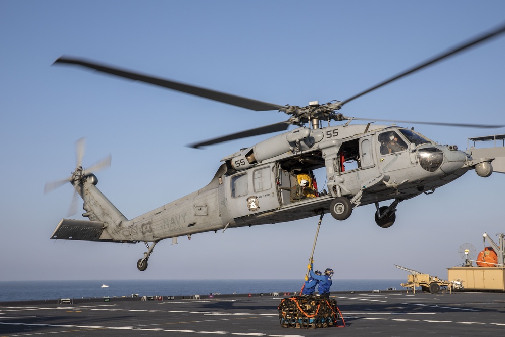 Aviation Boatswain’s Mate Airman Jacobi Easterling, left, and Airman Salva Kritzer attach cargo to an MH-60S Sea Hawk from Helicopter Sea Combat Squadron (HSC) 23 aboard expeditionary sea base USS Miguel Keith (ESB 5)