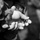 A black and white close-up photograph showing a pair of small hands, likely belonging to a child, cupping and holding a small insect or bug. The subject is wearing what appears to be a jacket or outdoor clothing visible in the blurred background. The shallow depth of field keeps focus on the hands and the small creature being held.