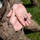 A person wearing U.S. Marine Corps digital camouflage (MARPAT) uniform holds out an open palm displaying a small Eagle, Globe, and Anchor (EGA) insignia pin. The hands appear dirty and worn, suggesting recent physical activity or training. This image likely documents a Marine Corps graduation or qualification event where the EGA is traditionally awarded.