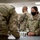 Combat aircraft integrate in Hawaii for exercise Sentry Aloha-21 The image shows U.S. Air Force personnel in OCP (Operational Camouflage Pattern) uniforms gathered in what appears to be an indoor briefing or administrative area. All visible individuals are wearing black face masks, suggesting this was taken during the COVID-19 pandemic period. A female airman in the foreground appears to be at a table interacting with another service member.