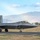 Combat aircraft integrate in Hawaii for exercise Sentry Aloha-21 An F-22 Raptor stealth fighter jet is taxiing on a runway at what appears to be Joint Base Pearl Harbor-Hickam in Hawaii, identifiable by the 'HH' tail code and serial number AF 05-053. The aircraft is painted in standard gray stealth coating and has its landing gear deployed. A mountainous tropical landscape and palm trees are visible in the background.