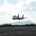Combat aircraft integrate in Hawaii for exercise Sentry Aloha-21 A military jet fighter, identifiable as an F-15 Eagle, is captured at the moment of takeoff from a runway with afterburners fully engaged, producing visible orange flame from both engines. The aircraft is flying extremely low over the tarmac in a near-horizontal attitude at high speed. In the background, a mountain range — consistent with Diamond Head crater in Honolulu, Hawaii — and a city skyline are visible.