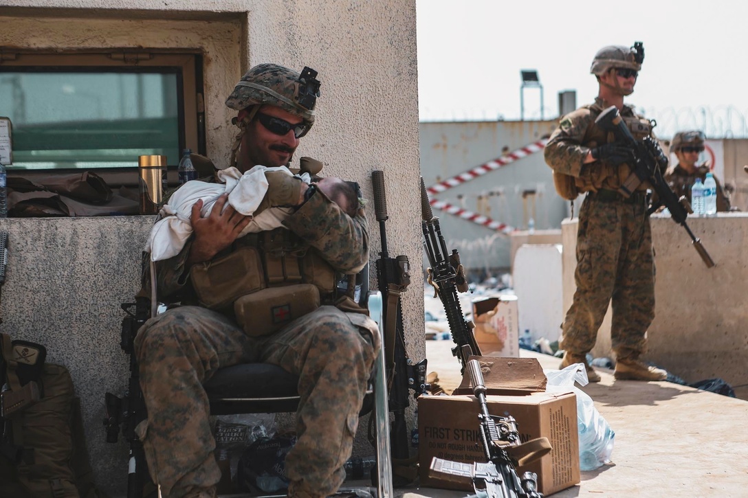 A Marine assigned to the 24th Marine Expeditionary Unit (MEU) calms an infant during an evacuation at Hamid Karzai International Airport, Kabul, Afghanistan, Aug. 20. U.S. service members and coalition partners are assisting the Department of State with a Non-combatant Evacuation Operation (NEO) in Afghanistan. (U.S. Marine Corps photo by Sgt. Isaiah Campbell)