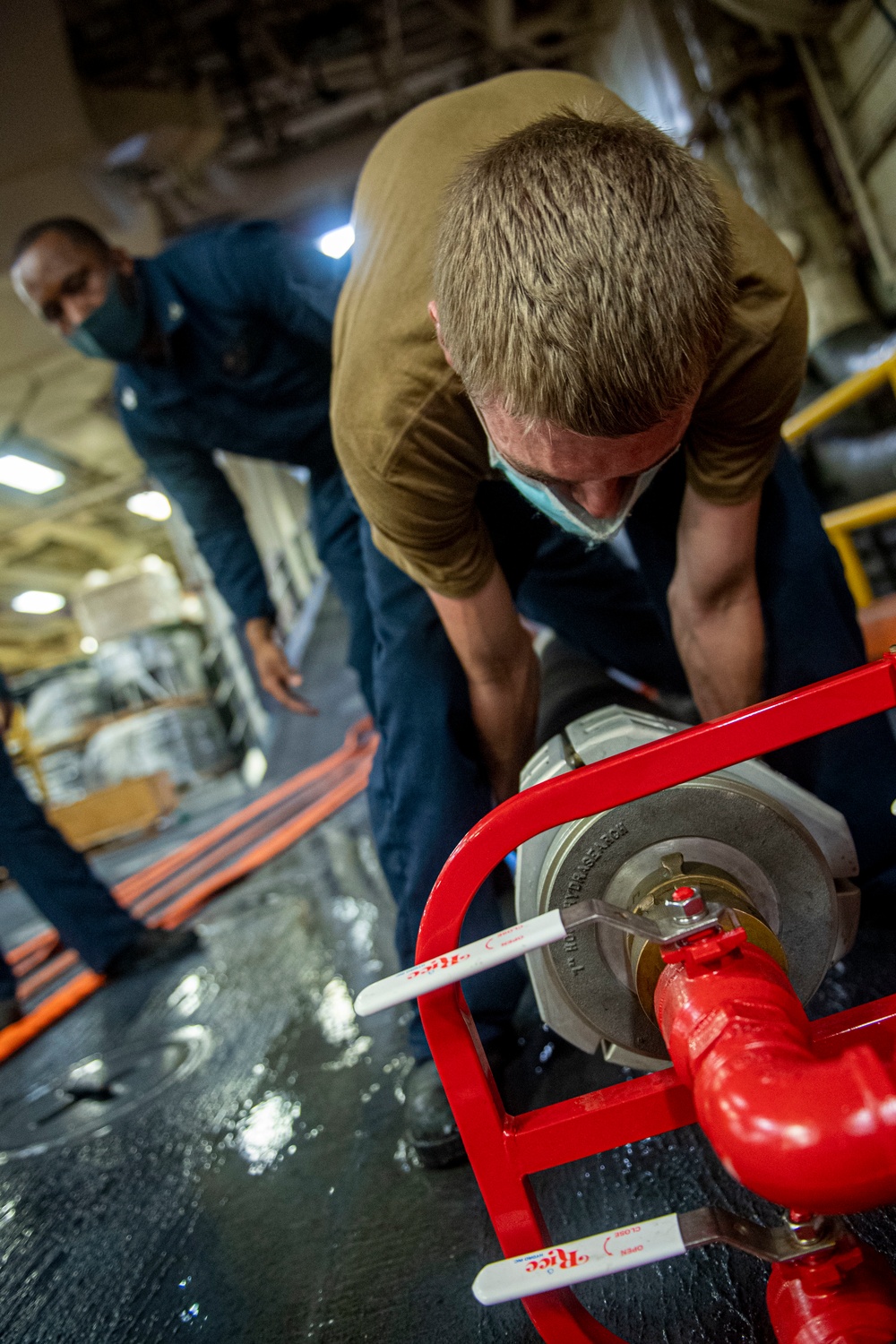 Sailors assigned to the USS America conduct maintenance in the vehicle storage area.