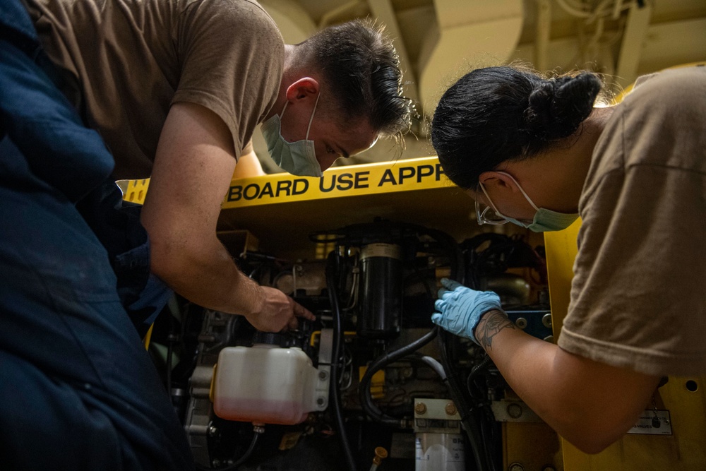 Sailors assigned to the USS America conduct maintenance in the vehicle storage area.