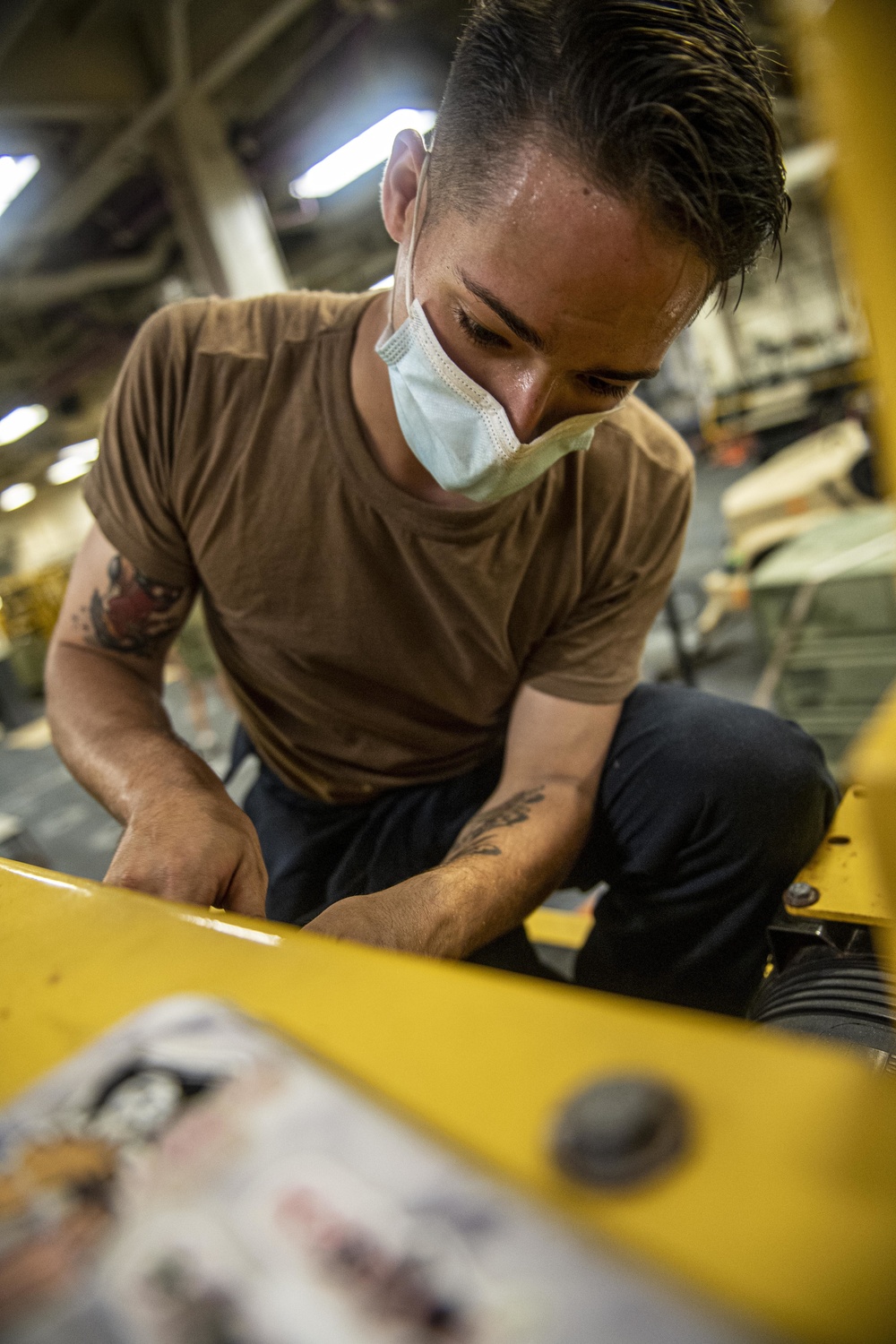 Sailors assigned to the USS America conduct maintenance in the vehicle storage area.