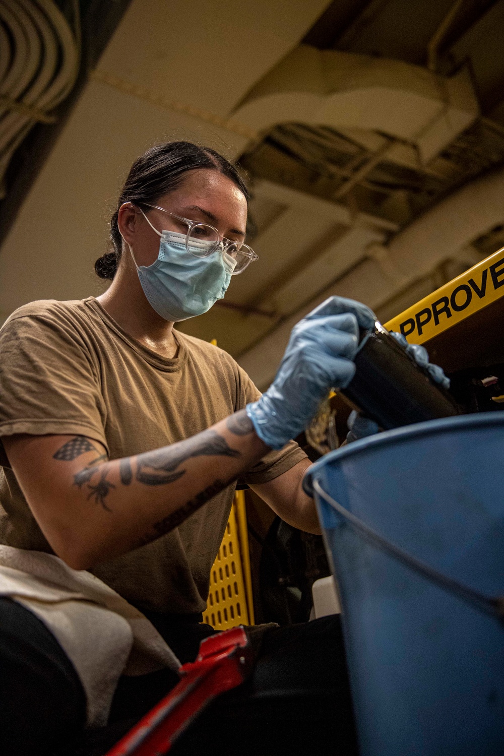 Sailors assigned to the USS America conduct maintenance in the vehicle storage area.