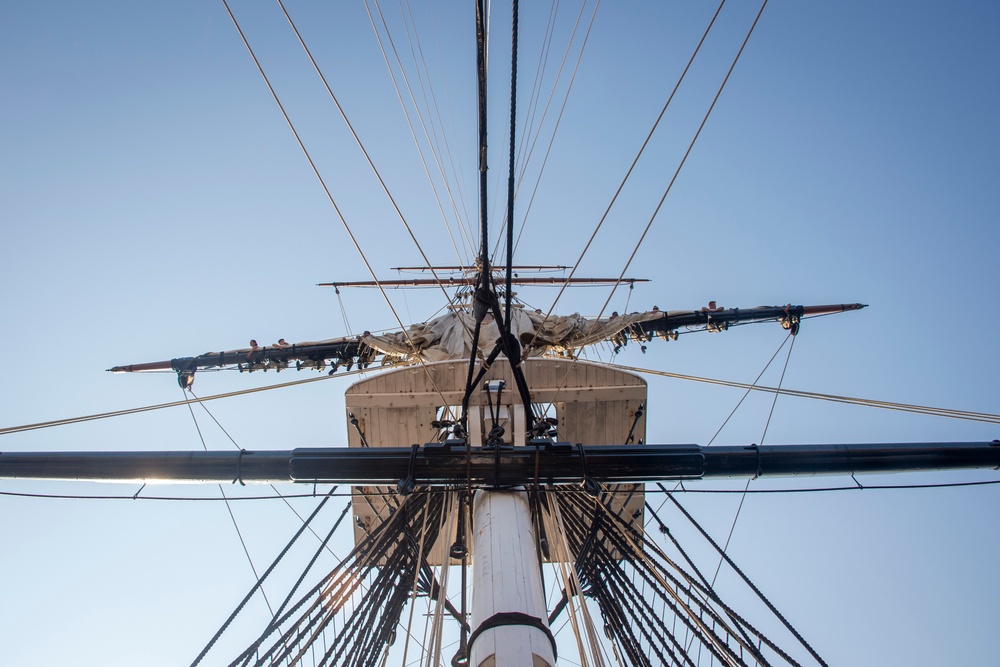 Sailors furl main top sail aboard USS Constitution