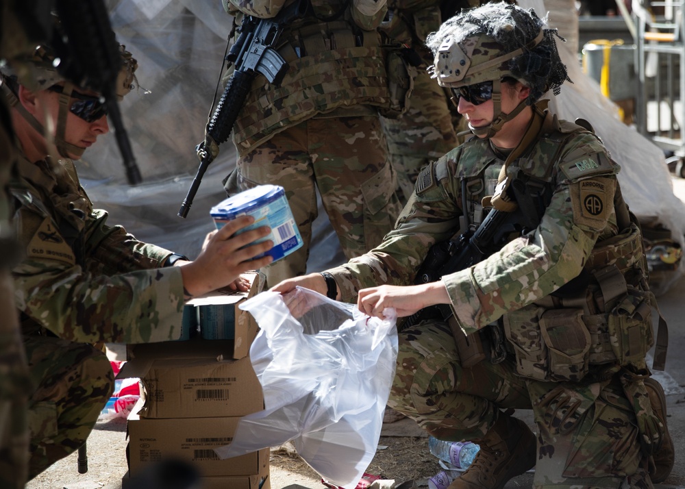 Paratrooper with the 82nd Airborne Division Places Baby Formula into one of the Care Bags