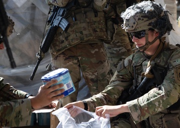 Paratrooper with the 82nd Airborne Division Places Baby Formula into one of the Care Bags
