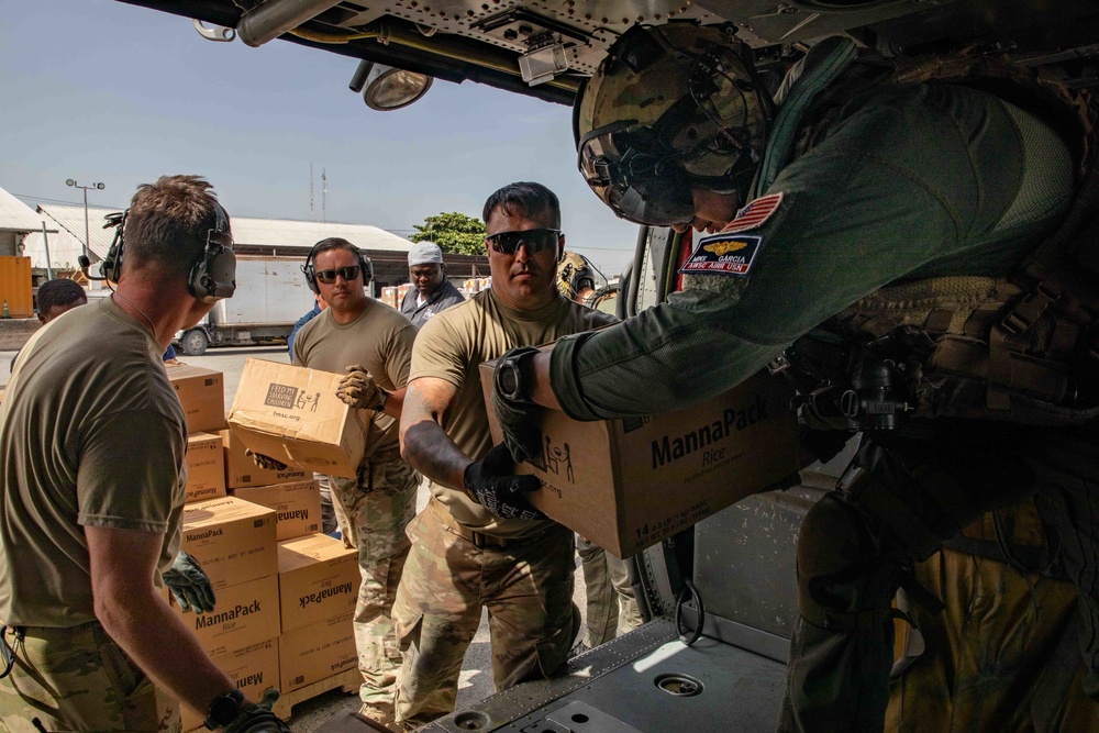 Army Soldiers Help Load A Navy MH-60S Sea Hawk Helicopter With Humanitarian Aid