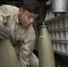 Service Member loads a 155mm Round into an armored carrier