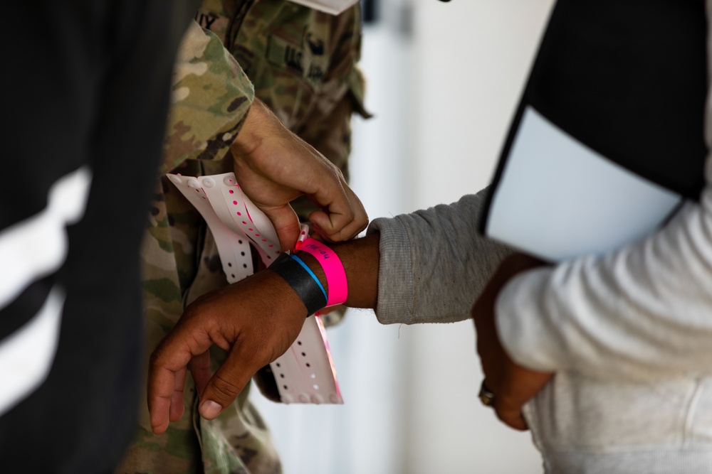 U.S. Army Soldier places a wristband on Afghan evacuee during Operation Allies Welcome at Fort Pickett, Virginia.