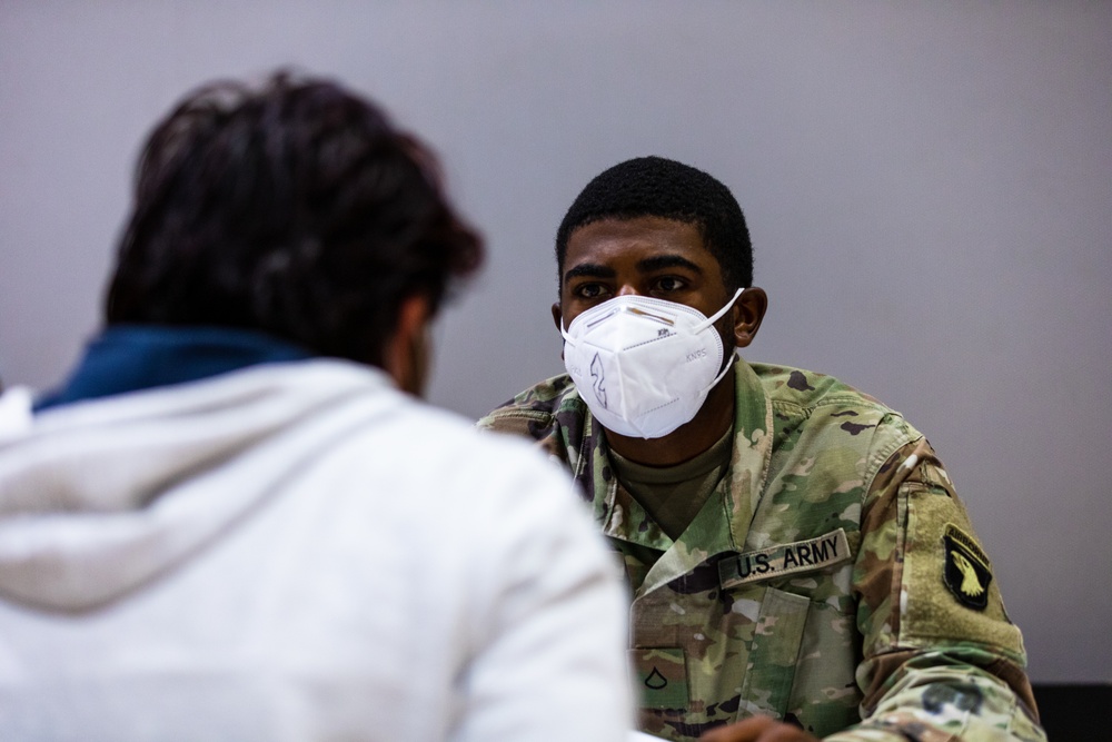 U.S. Army Soldier helps Afghan evacuees begin their In-Processing during Operations Allies Welcome at Fort Pickett, Virginia.