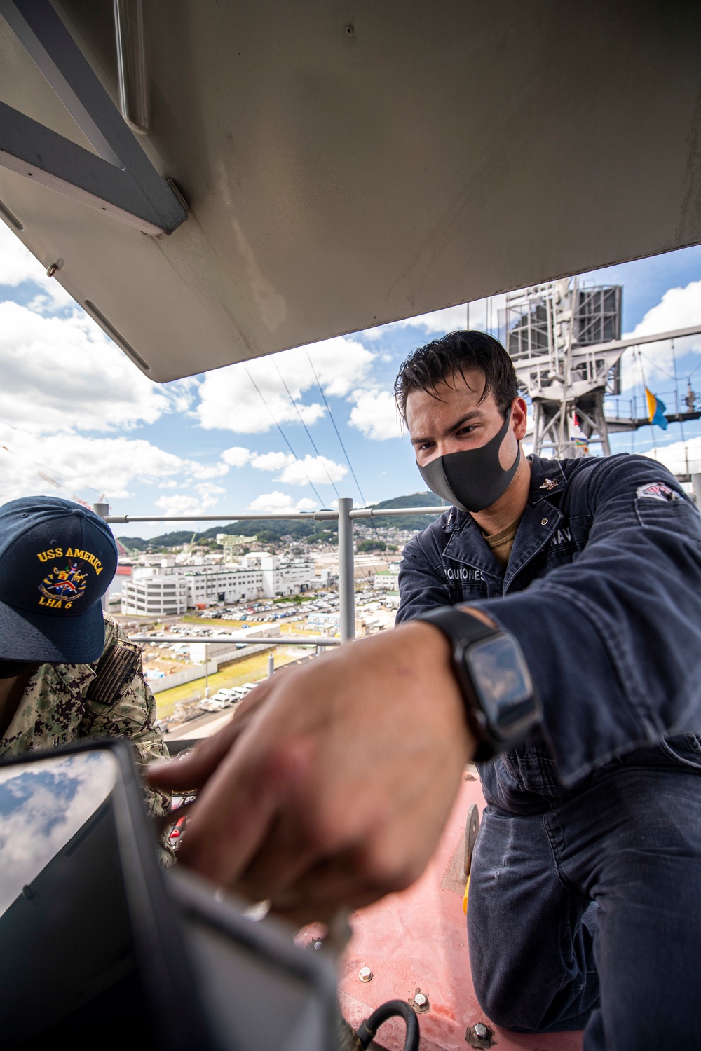 Sailors assigned to the forward deployed amphibious assault ship USS America perform maintenance on one of the ships radars.