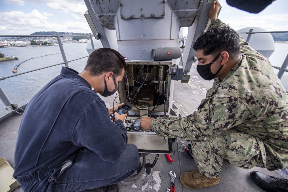 Sailors assigned to the forward deployed amphibious assault ship USS America perform maintenance on one of the ships radars.