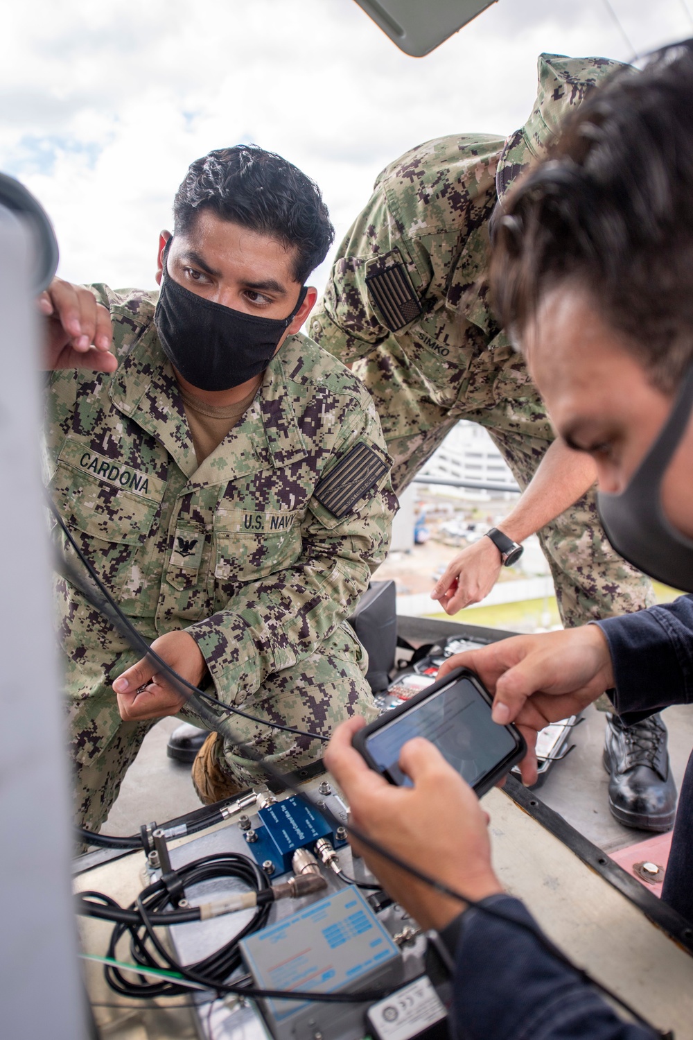 Sailors assigned to the forward deployed amphibious assault ship USS America perform maintenance on one of the ships radars.