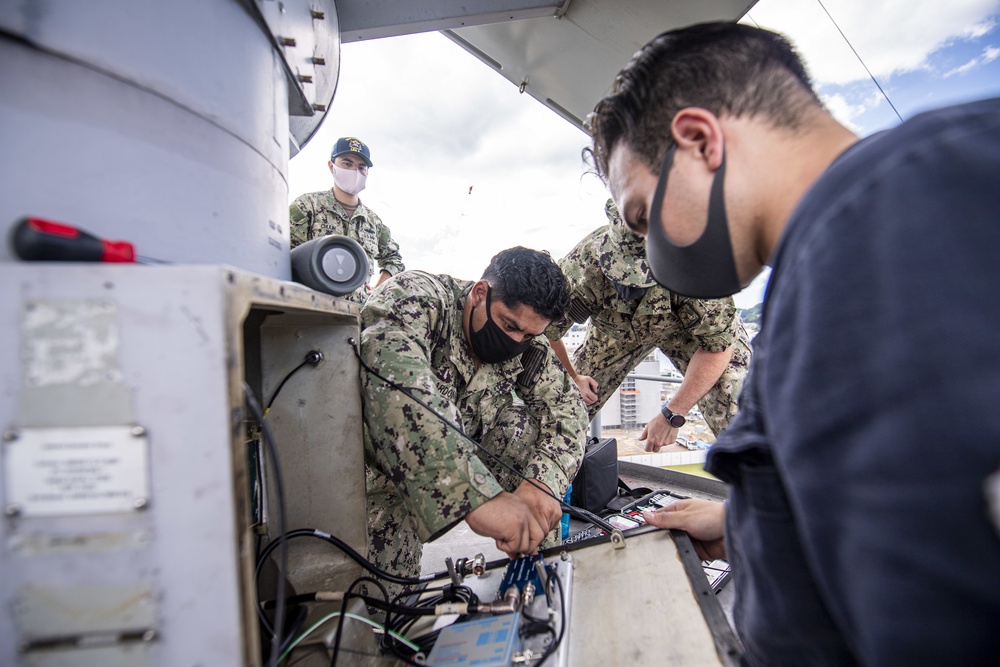 Sailors assigned to the forward deployed amphibious assault ship USS America perform maintenance on one of the ships radars.