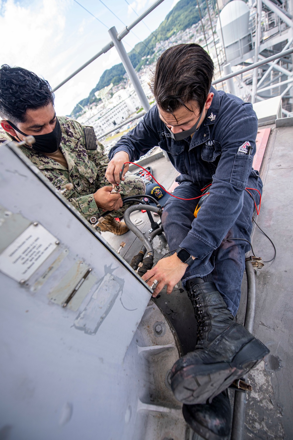 Sailors assigned to the forward deployed amphibious assault ship USS America perform maintenance on one of the ships radars.