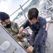 Sailors assigned to the forward deployed amphibious assault ship USS America perform maintenance on one of the ships radars.