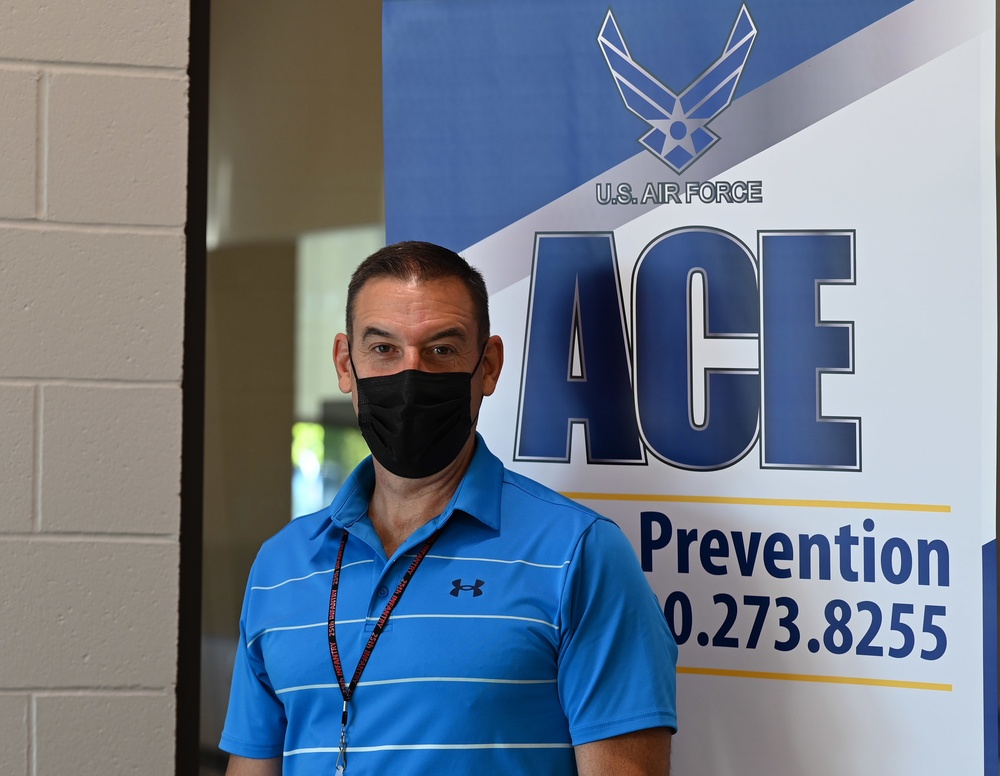 Violence Prevention Coordinator stands near an ACE banner at a Suicide Prevention Awareness event.