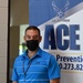 Violence Prevention Coordinator stands near an ACE banner at a Suicide Prevention Awareness event.