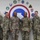 Seven U.S. Army personnel in MultiCam/OCP camouflage uniforms pose for a formal group photo in front of a wall displaying multiple military unit patches and insignia. The large circular emblem in the center background appears to be associated with U.S. Army Central (ARCENT). Name tapes are visible on several individuals, including Russell, Clark, Bartlett, McCullar, and Faucci.
