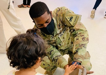 1st Lt. Roderick Britt, of 1st Battalion, 6th Infantry Regiment, 2nd Armored Brigade Combat Team, attends to a little girl after she was fitted for and received new shoes at the Doña Ana shoe-only donation building.