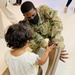 1st Lt. Roderick Britt, of 1st Battalion, 6th Infantry Regiment, 2nd Armored Brigade Combat Team, attends to a little girl after she was fitted for and received new shoes at the Doña Ana shoe-only donation building.