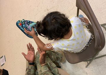 1st Lt. Roderick Britt, 1st Battalion, 6th Infantry Regiment, 2nd Armored Brigade Combat Team, attends to a little girl after she was fitted for and received new shoes at the Doña Ana shoe-only donation building.