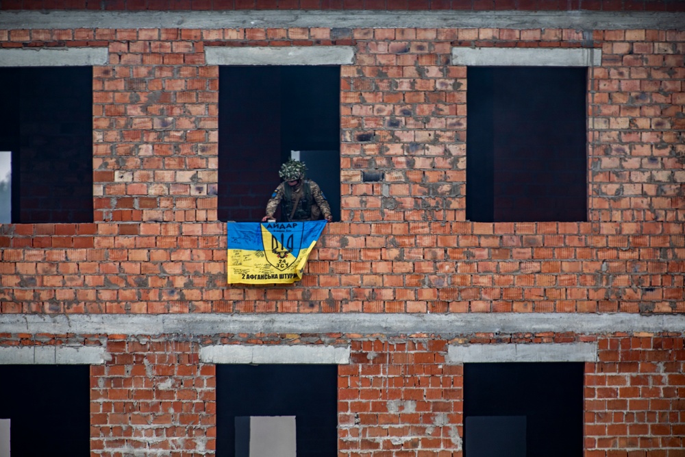 Ukrainian soldier puts flag on cleared building during Rapid Trident 21
