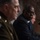 SECDEF, CJCS, CENTCOM Senate Armed Services Testimony The image shows three individuals seated at what appears to be a formal hearing or official proceeding. The central figure in sharp focus is a man wearing a dark suit with a blue tie and glasses, with hands clasped. To the left, partially out of focus, is a person in military uniform with visible insignia.