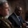 SECDEF, CJCS, CENTCOM Senate Armed Services Testimony The image shows two individuals seated at what appears to be a formal hearing or official proceeding. The person in focus is a man in a dark suit with a blue tie and glasses, appearing to speak or testify. In the foreground, out of focus, is a person wearing military-style attire.