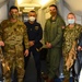Multinational service members and distinguished visitors pose for a photo